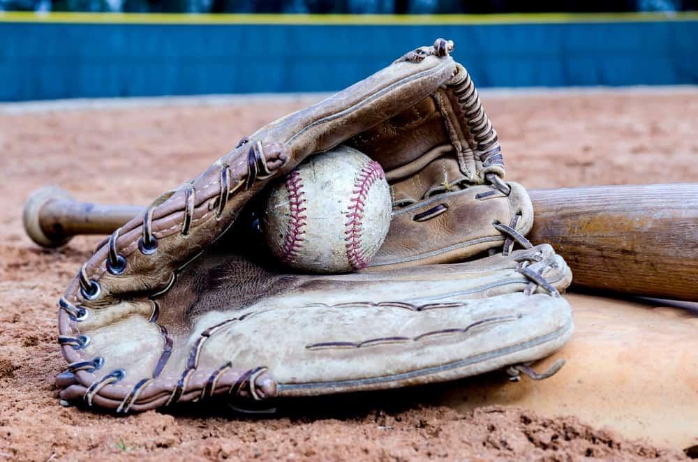 An old and used set of baseball bat, glove and ball.