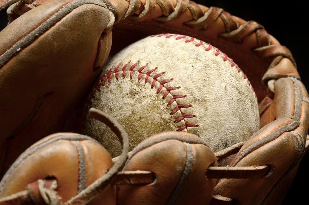 A close look at a leather baseball glove holding a ball.