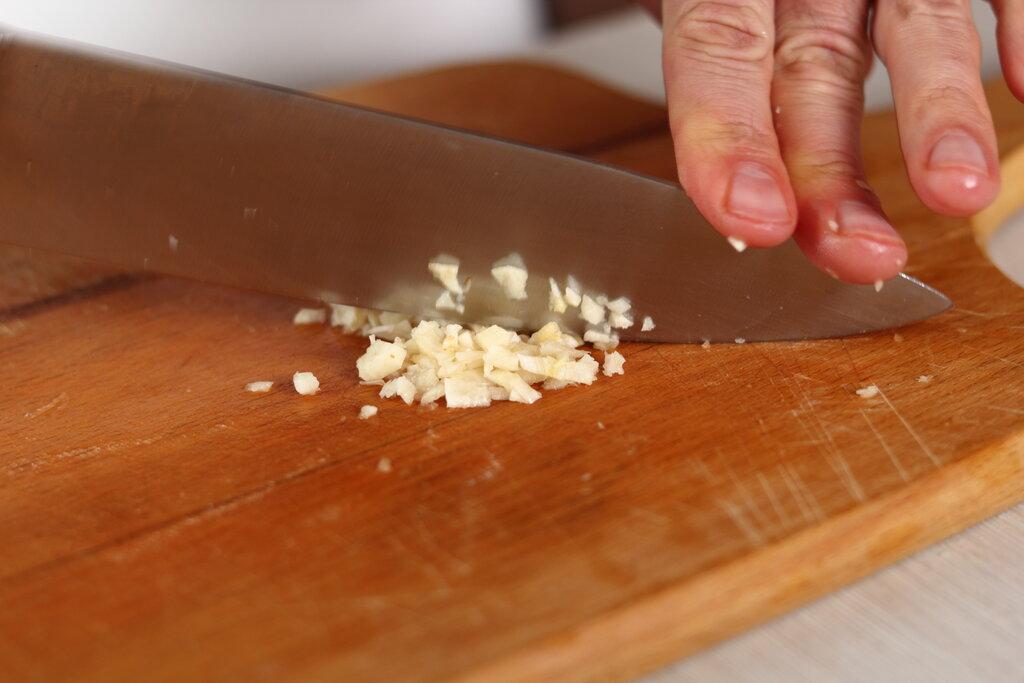 person mincing garlic with a knife