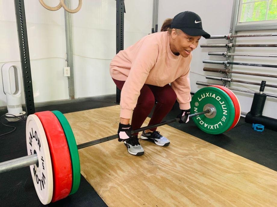 Woman performing deadlifts with trideer padded weightlifting gloves