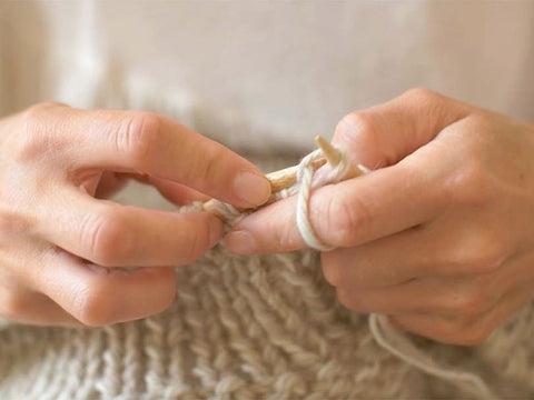 Woman knitting a blanket or scarf. Hand care is important so that we can continue doing what