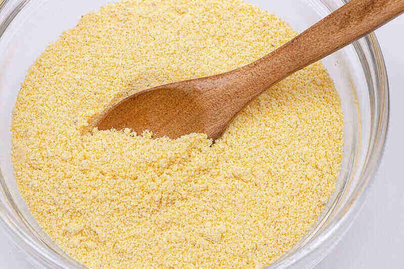 close-up of corn mean flour in a bowl with a wooden spoon