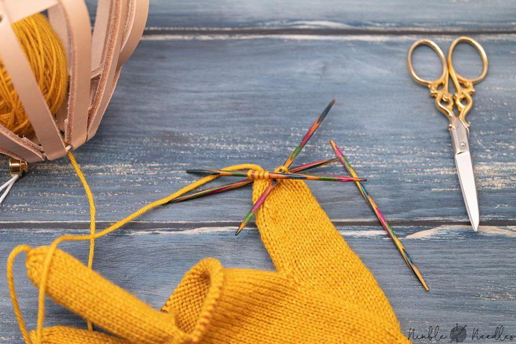 close up shot of someone knitting the thumb of a glove