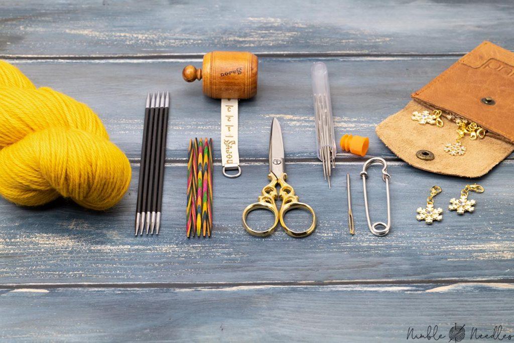 materials and tools you need to knit a gloves aligned on a desk