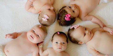 Five babies with different-colored bows in their hair