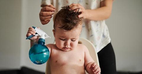 A mom putting coconut oil onto her baby's hair