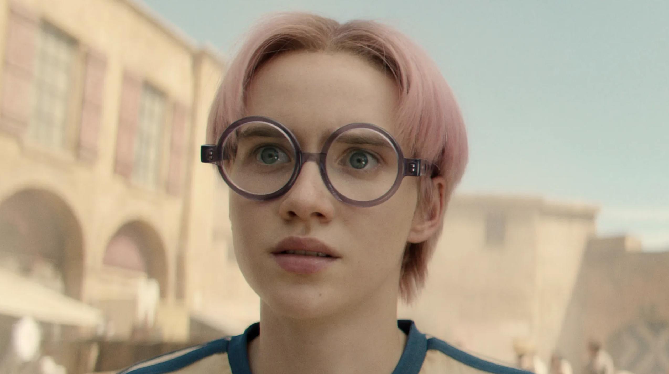 Morgan Davies, wearing circular glasses, stares incredulously off camera in a scene from Netflix