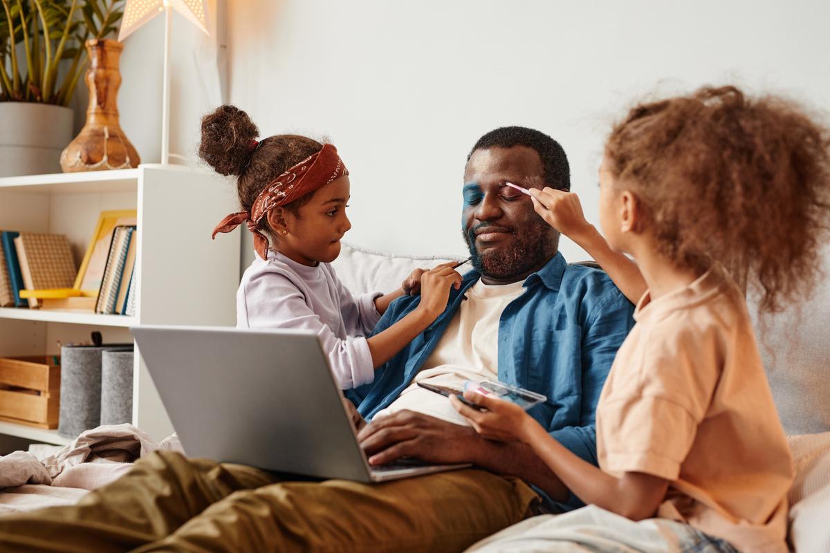 Daughters applying makeup on their father