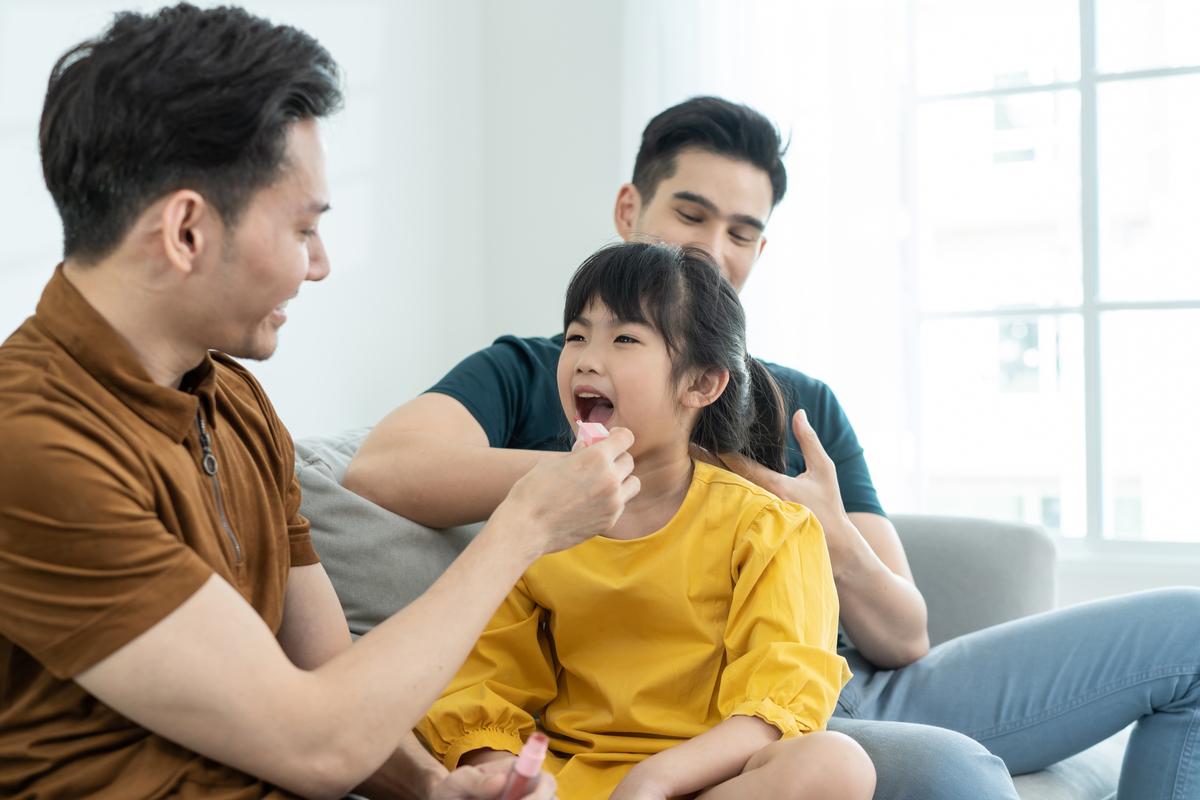 A father applying makeup to his young daughter