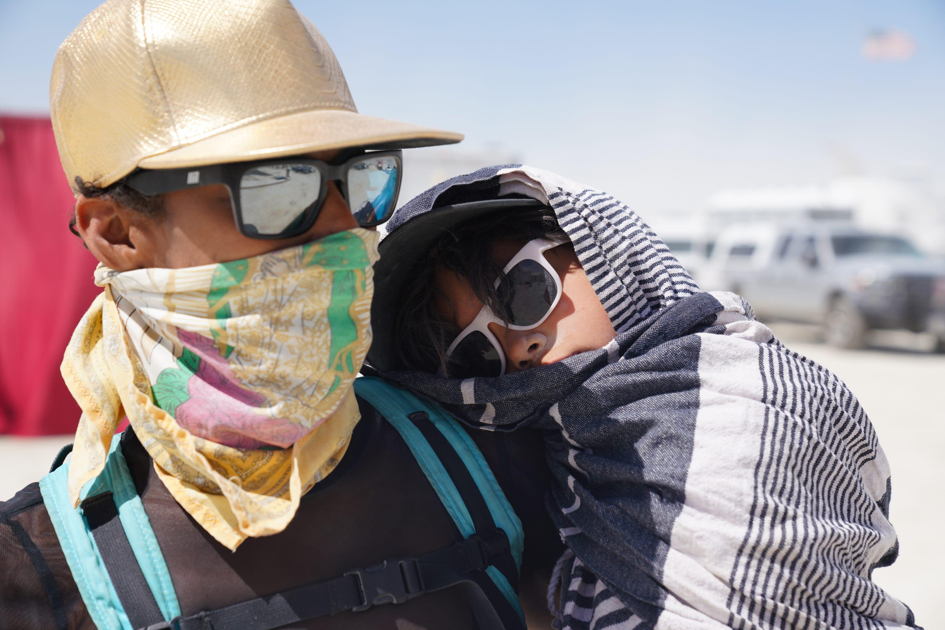 Tracie Williams of Portland carries her son, known at Burning Man as "Pool Boi 01" during a dust storm at the event.