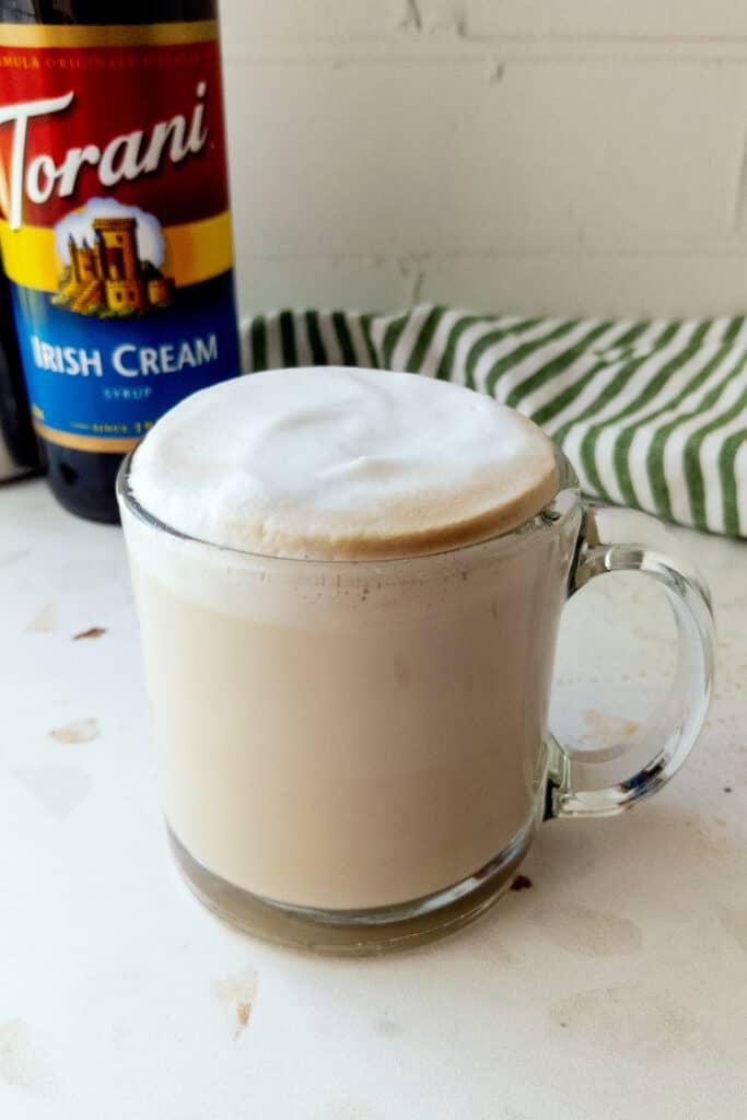 A hot Irish cream breve with a bottle of Torani Irish cream syrup in the background.