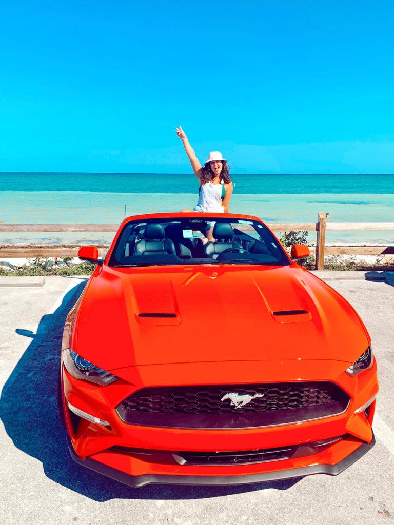 What to pack for the Florida Keys? A sun hat! Girl in a red convertible on the beach in the Florida Keys