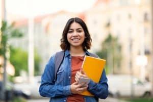 student smiling in camera holding an orange folder