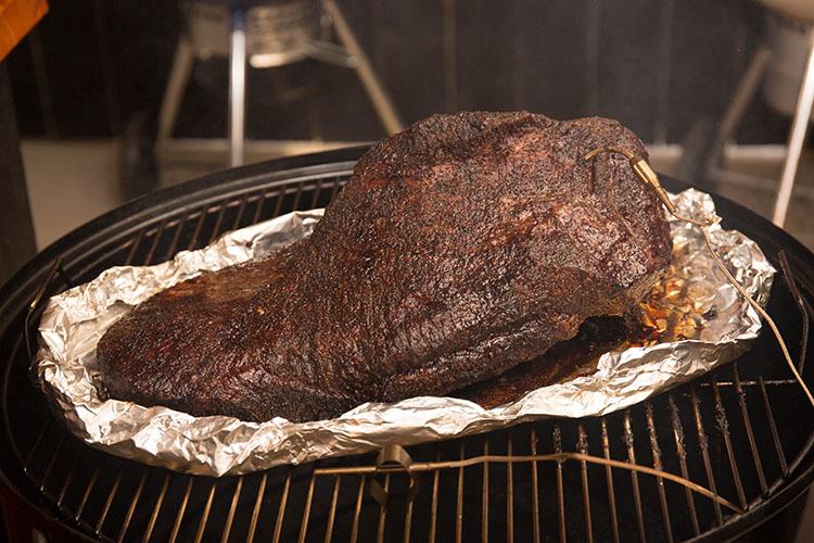 beef brisket boated in foil on a weber smokey mountain