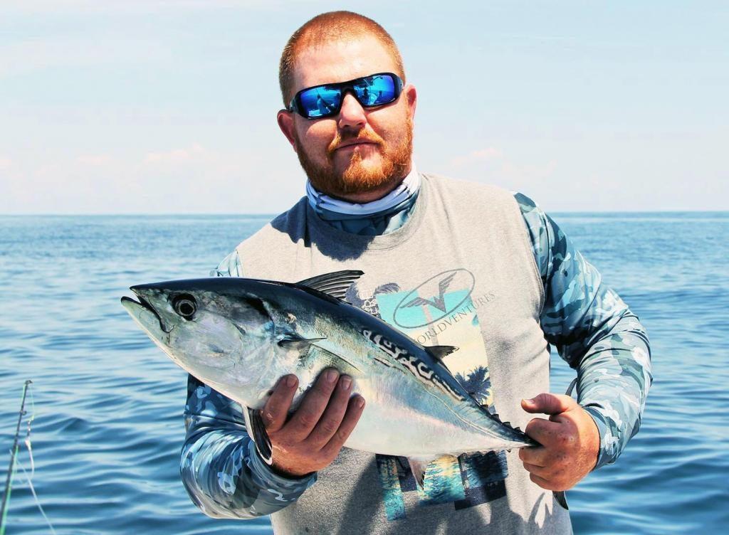 Tuna fishing: A smiling angler holding a Little Tunny