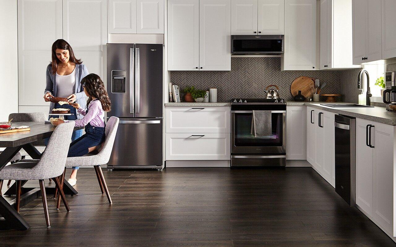 A mother and daughter sitting at a table in a kitchen with Whirlpool appliances