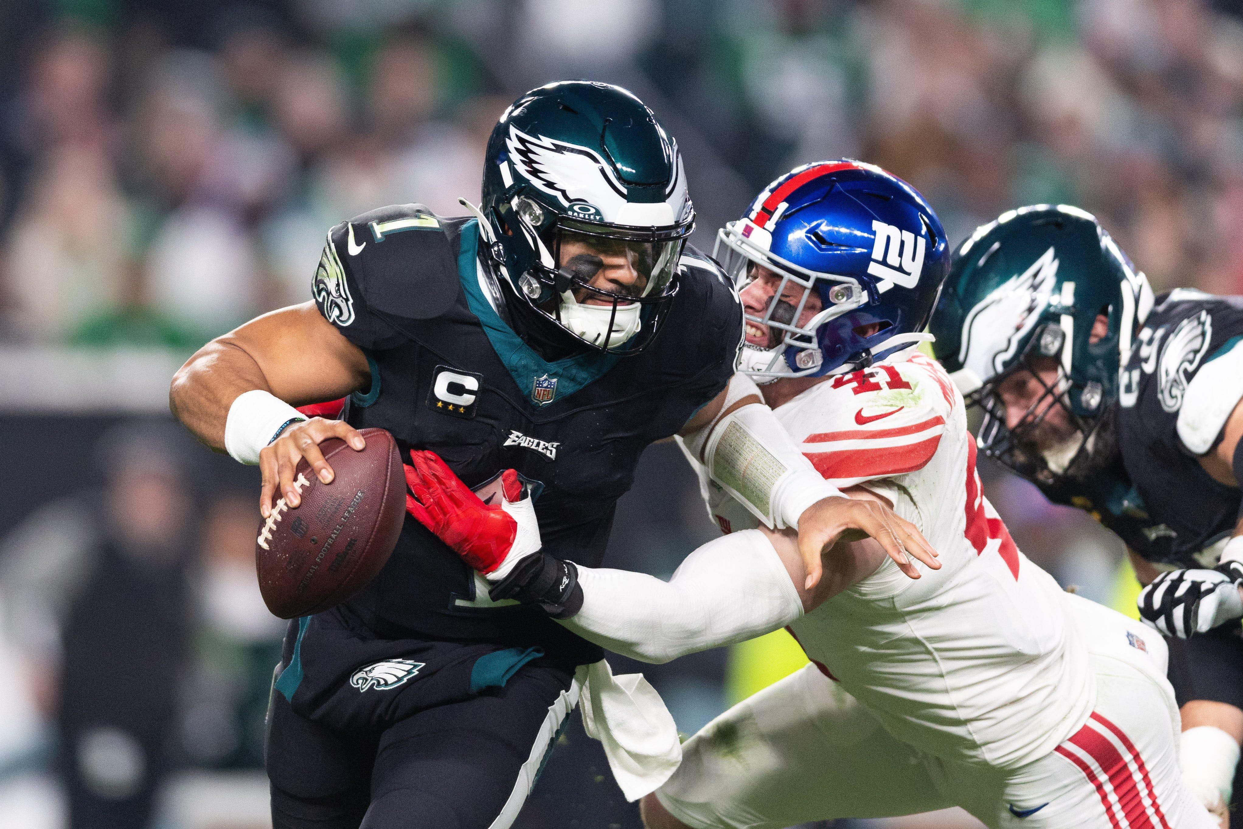 Dec 25, 2023; Philadelphia, Pennsylvania, USA; Philadelphia Eagles quarterback Jalen Hurts (1) eludes the tackle attempt of New York Giants linebacker Micah McFadden (41) during the second quarter at Lincoln Financial Field. Mandatory Credit: Bill Streicher-USA TODAY Sports