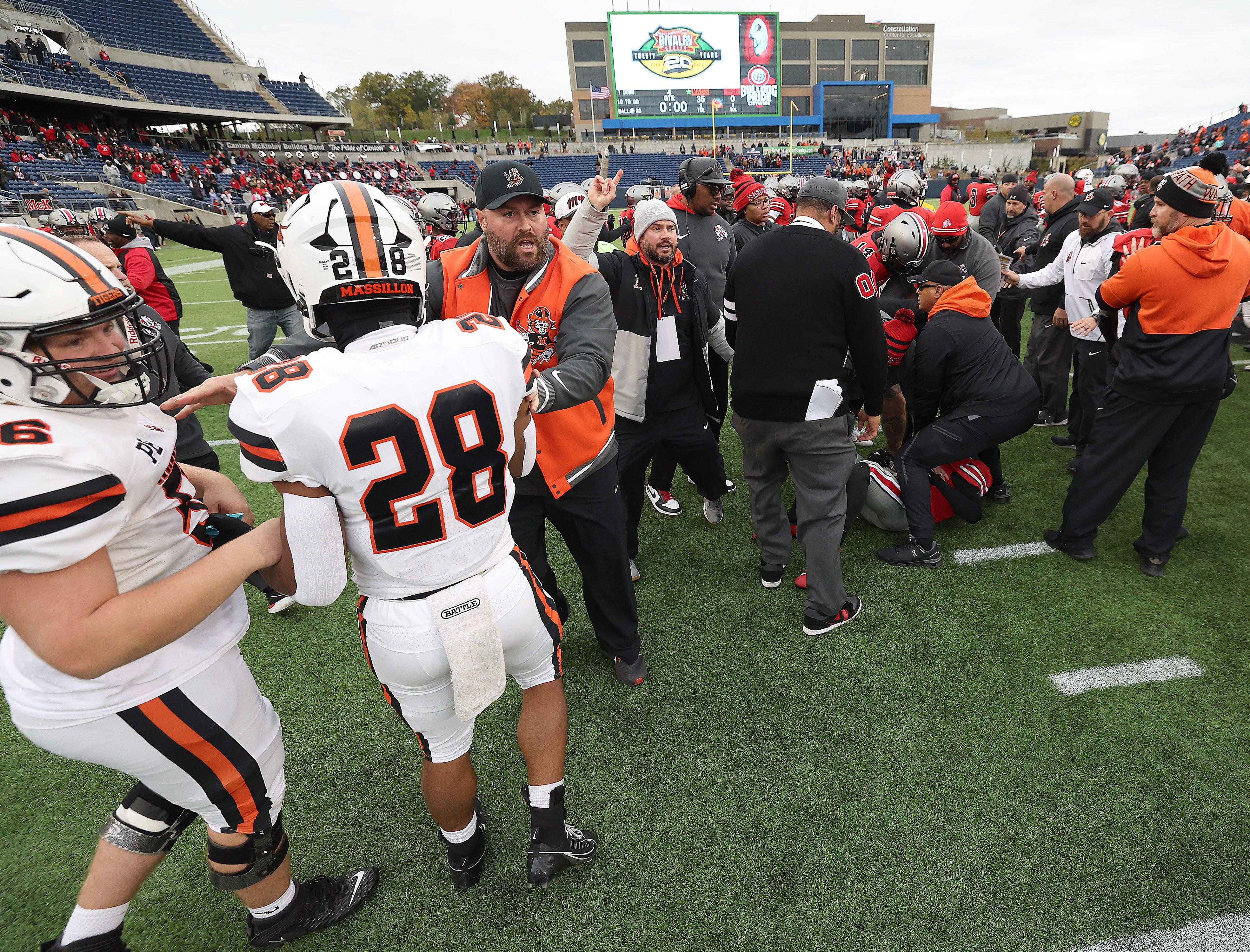 Massillon head coach Nate Moore and McKinley head coach Antonio Hall work to control their players during a melee at the end of their game Saturday, October 21, 2023.