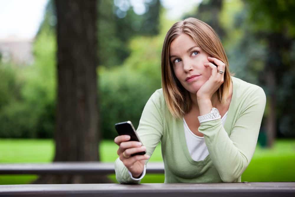 woman thinking while holding phone