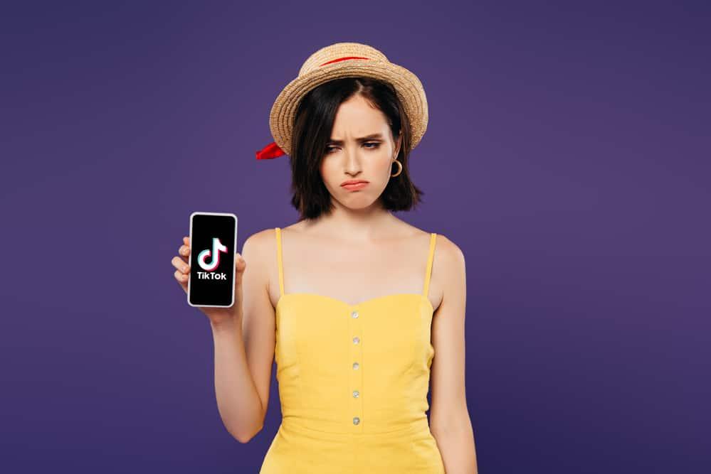 sad girl holding phone with tiktok