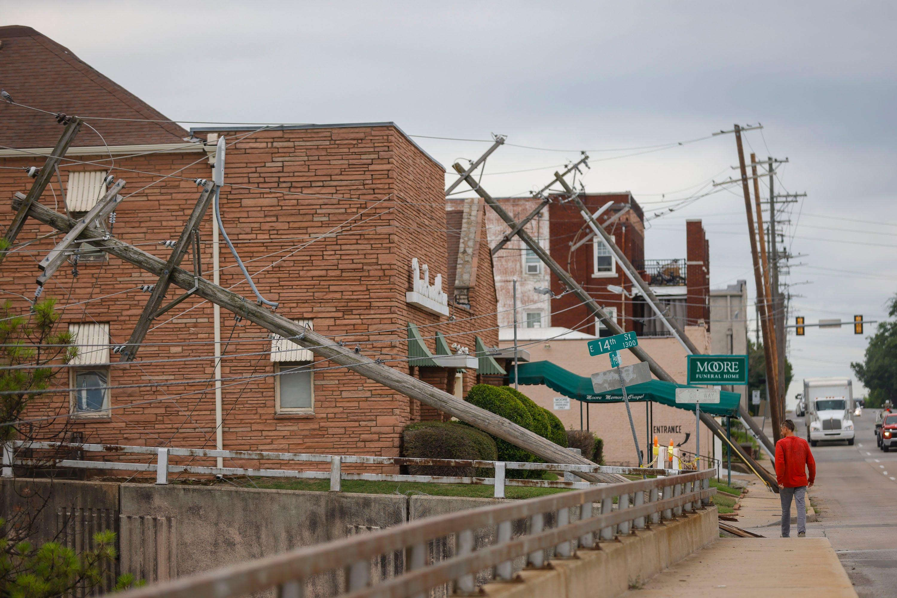 A man walks past downed power lines Tuesday on Peoria Avenue and 14th Street in Tulsa.