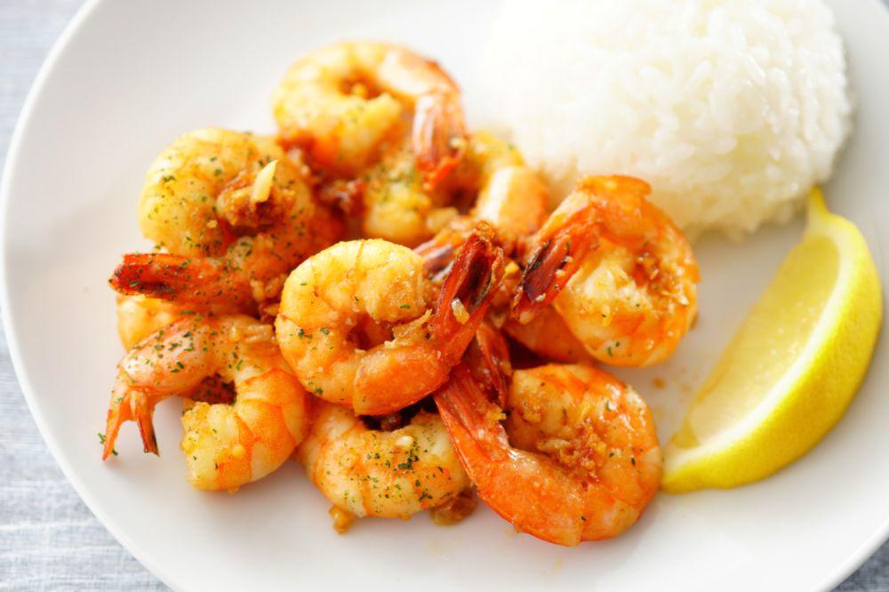 Garlic shrimp on a plate with rice and a lemon.