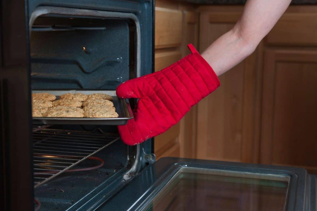 A woman removing freshly baked cookies on the oven