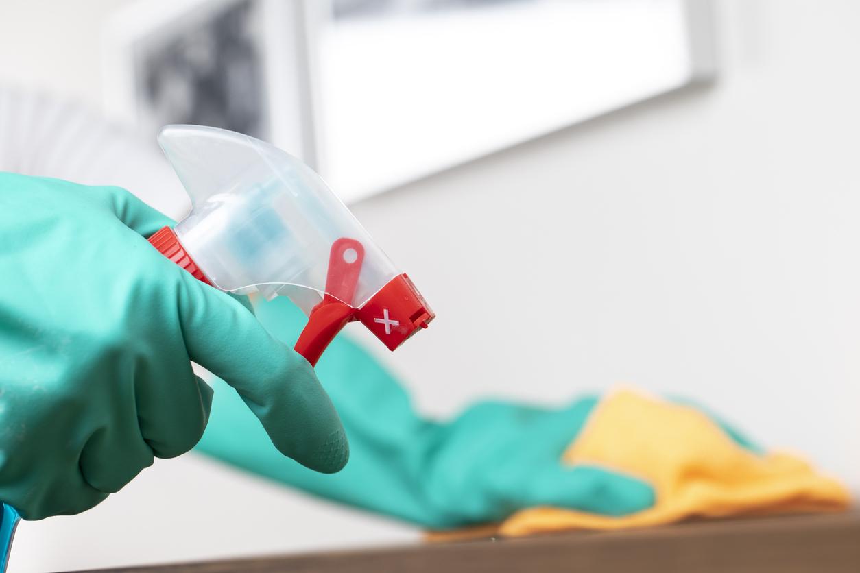 Woman in rubber gloves sprays a counter top with cleaner