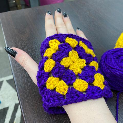 The purple and yellow granny squares have been joined together and are being worn on someone
