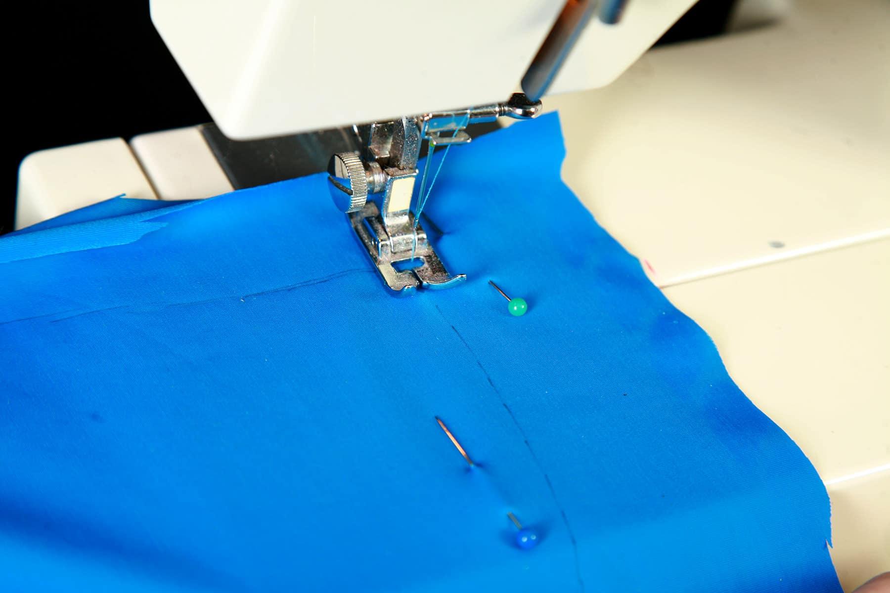 A sewing machine is set up to sew blue spandex fabric.