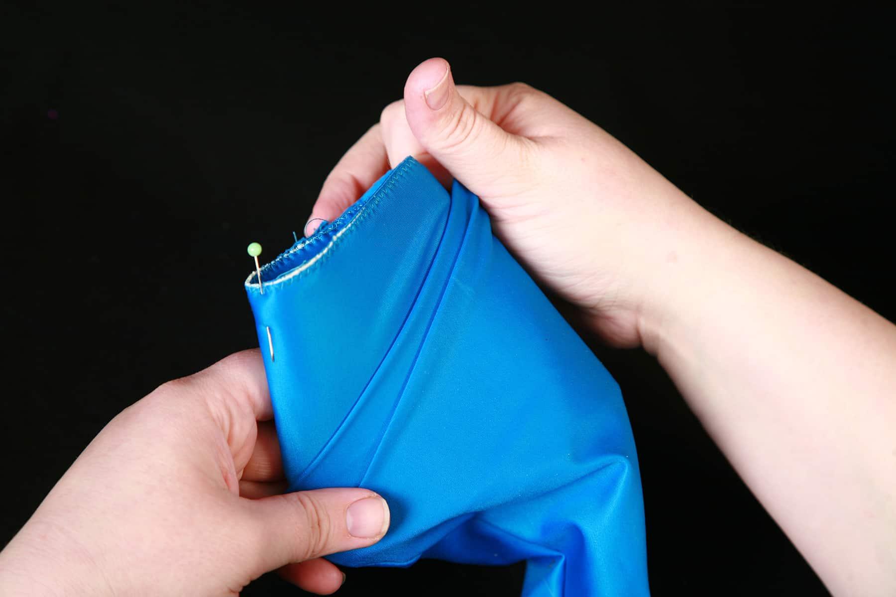 The sewn cuff is being placed inside the opening of a blue glove.