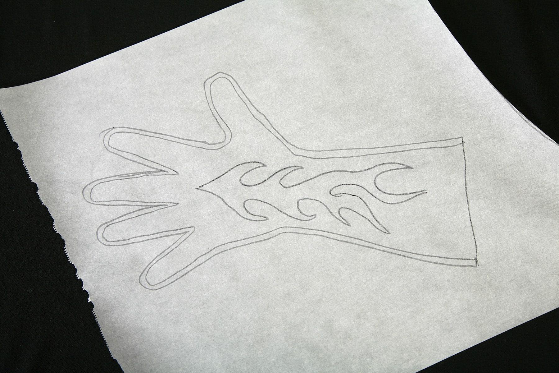 A glove pattern traced onto a piece of exam table paper. It has a flame design up the middle of it.