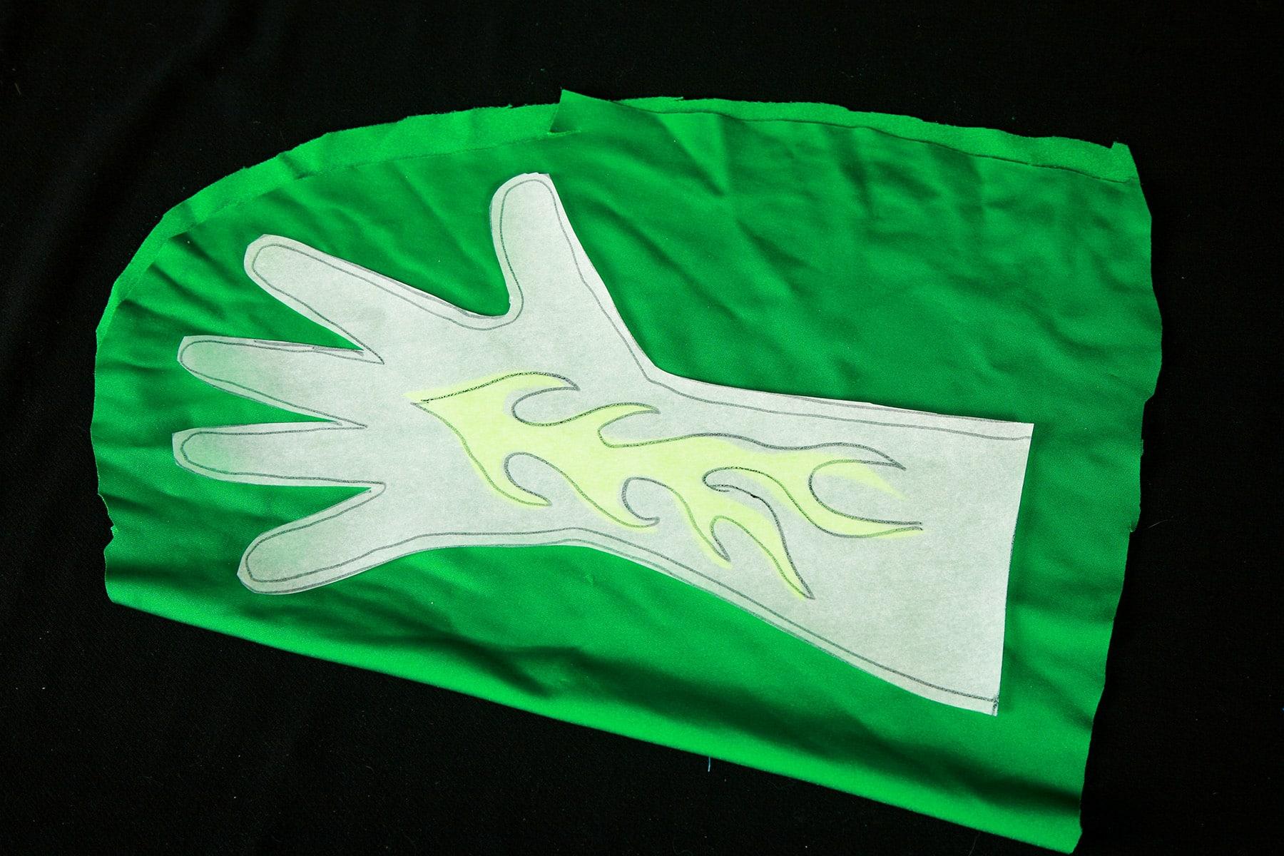 The glove pattern and flame are resting on top of a piece of dark green spandex.