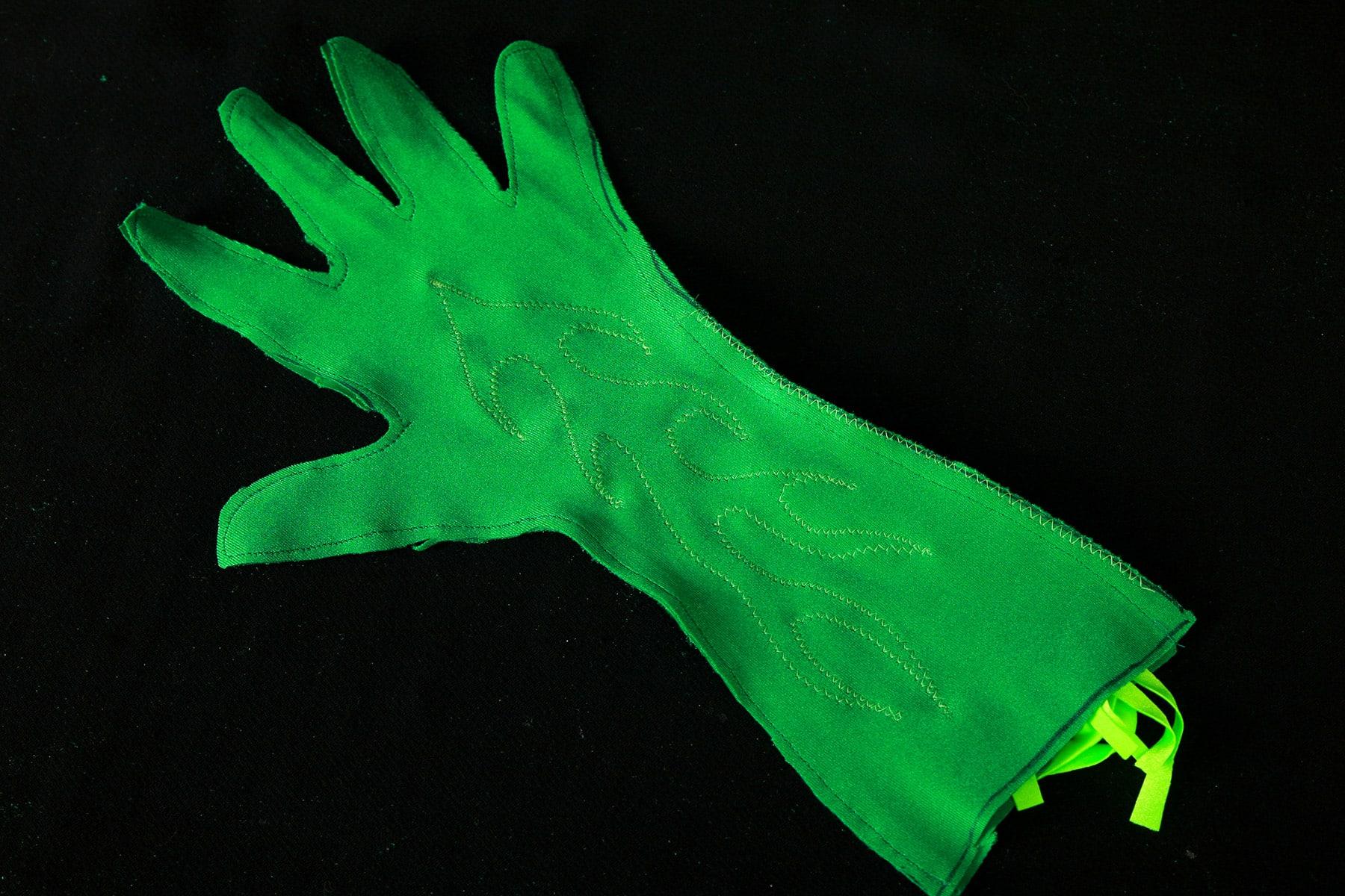 An inside out dark green spandex glove, against a black background.