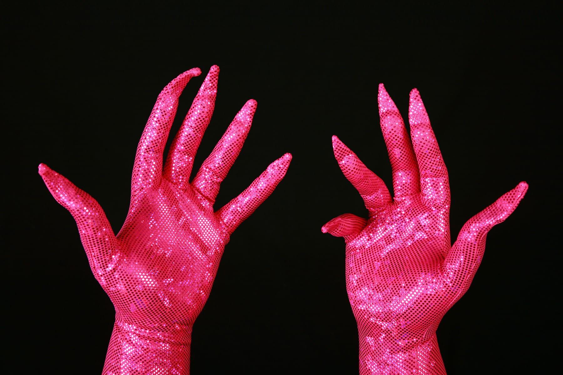 Two hands are shown wearing sparkly hot pink gloves, with built in claws.