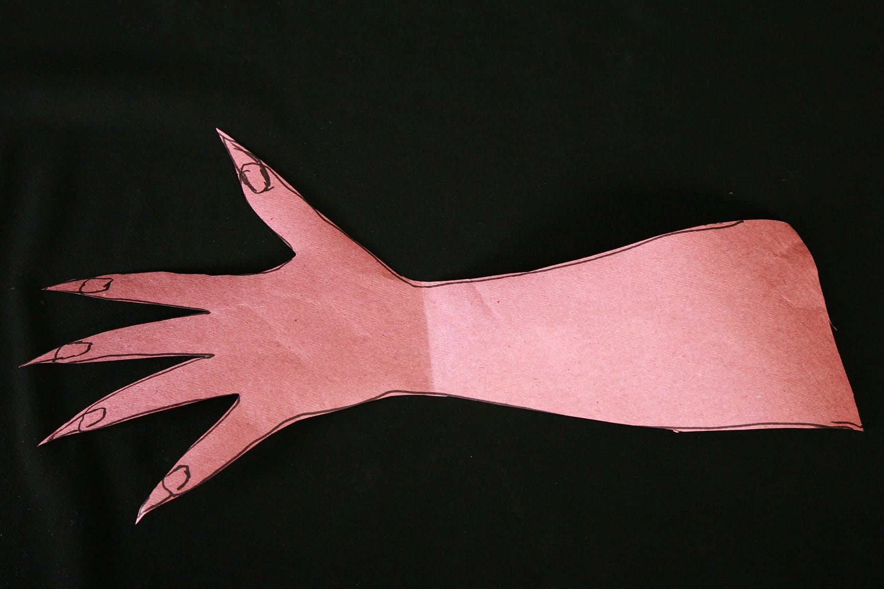 A glove pattern has been cut from pink rosin paper