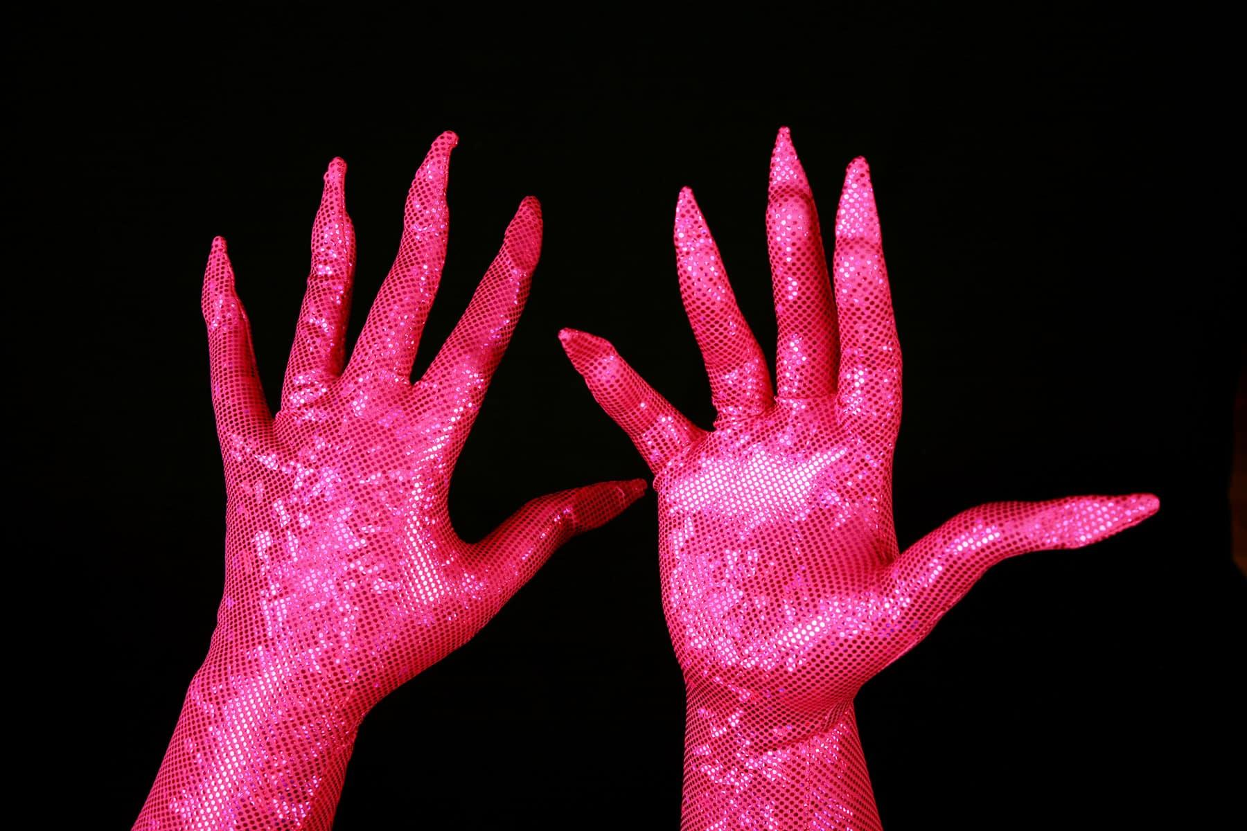 Two hands are shown wearing sparkly hot pink gloves, with built in claws.