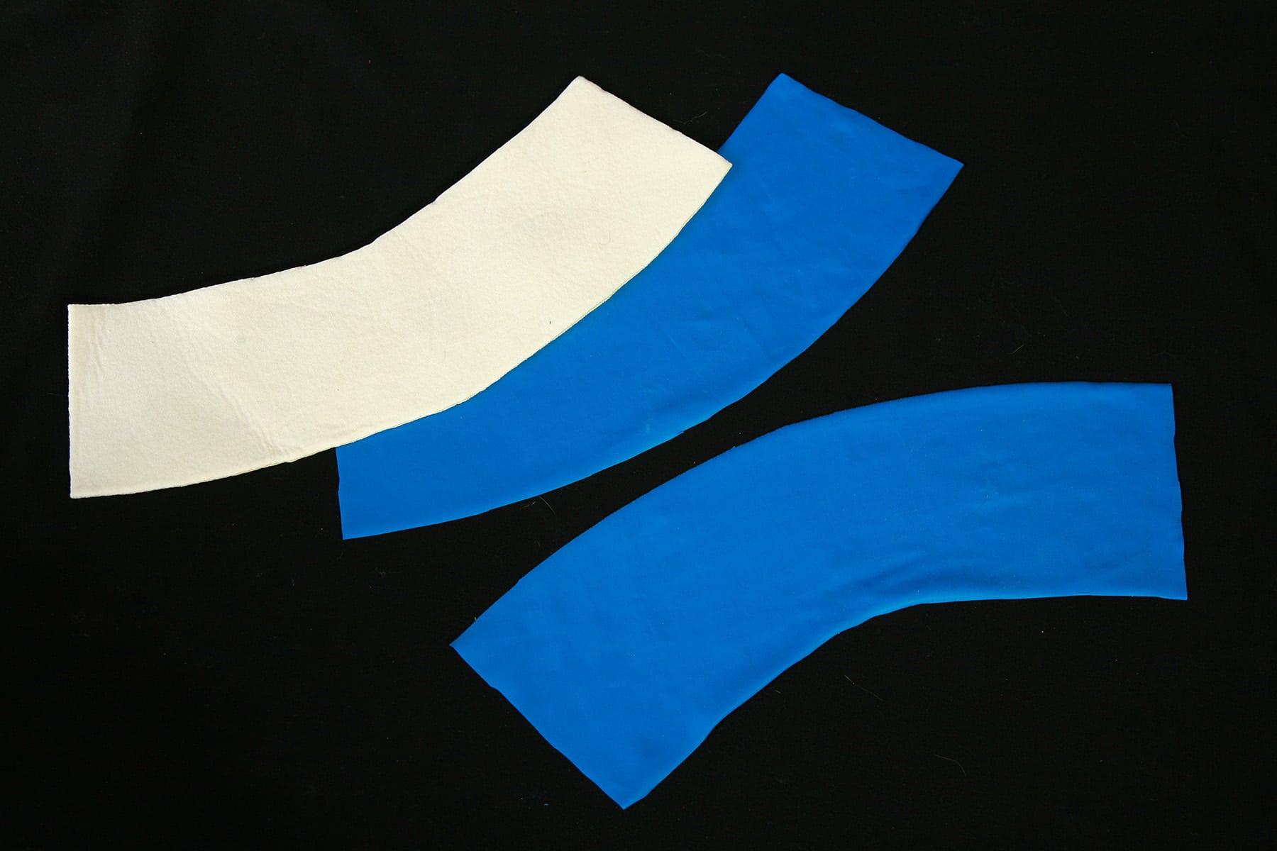 3 cuff pieces - 2 blue spandex pieces, 1 foam piece - laying on a black background.