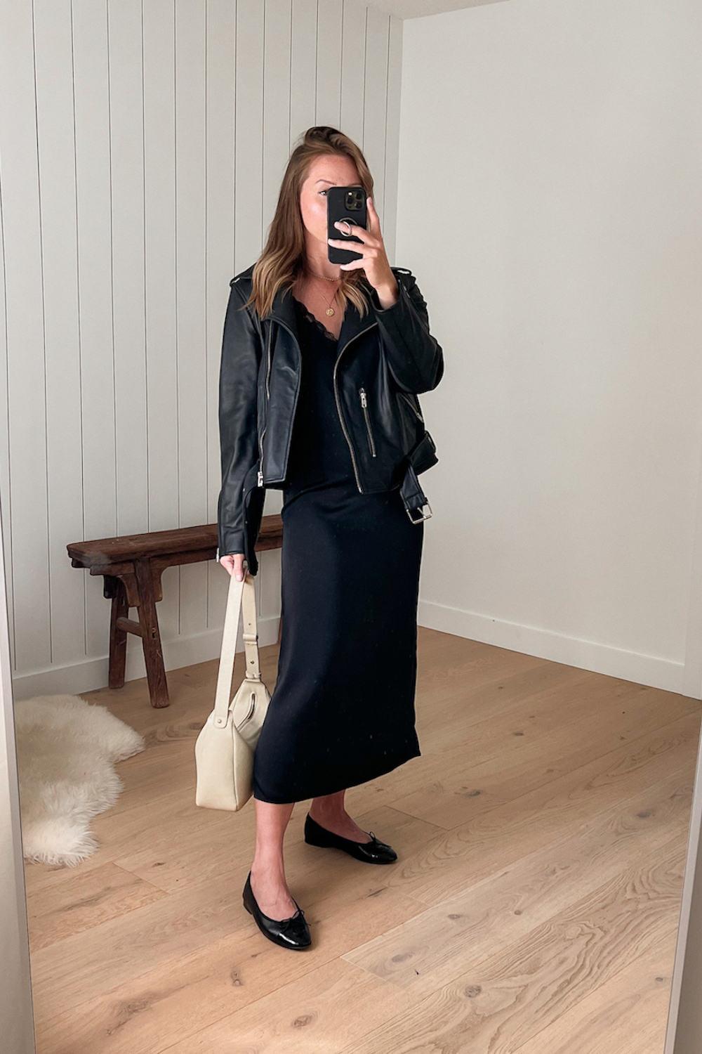 woman wearing a black leather jacket over a black slip dress with black Chanel ballet flats