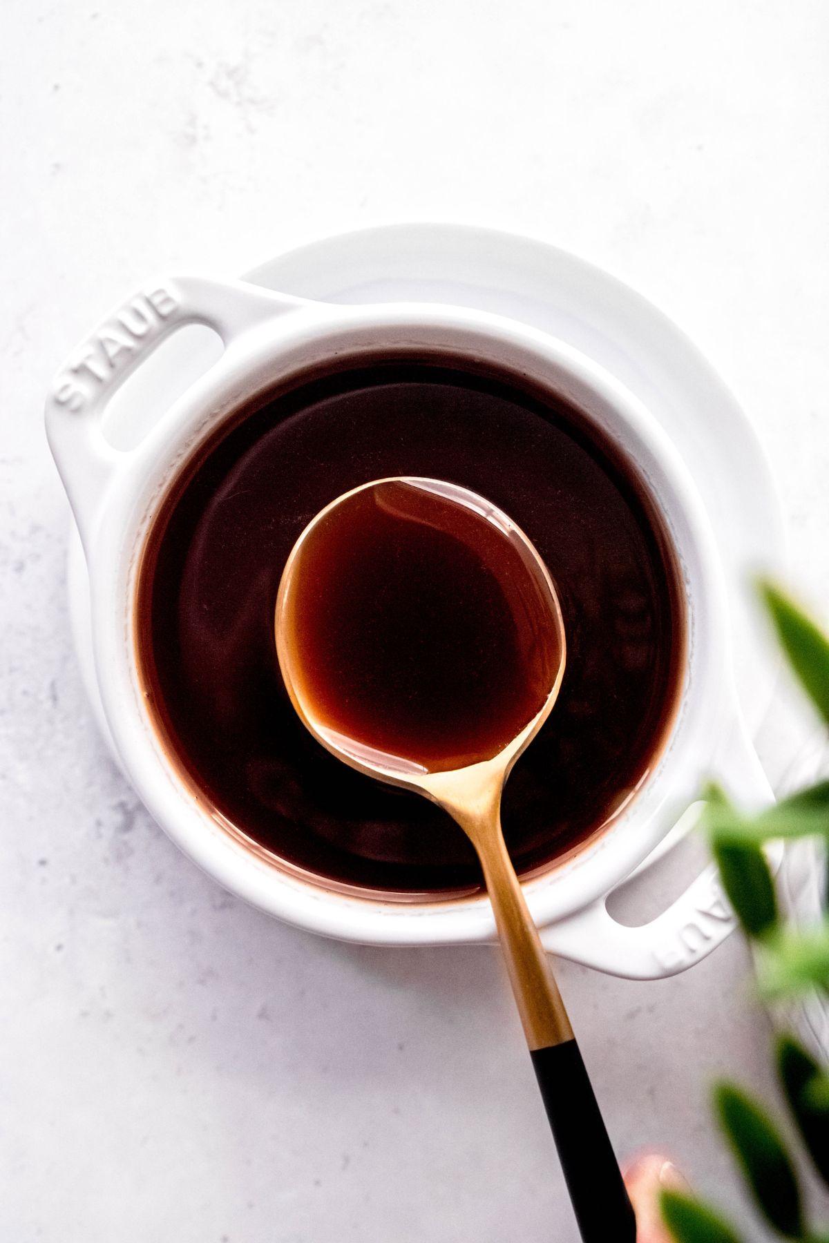 flat lay shot of a white bowl of Irish cream syrup with a gold spoon taking a portion from the bowl.