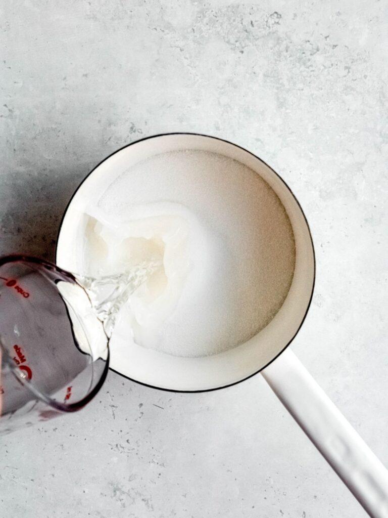 action shot of water being poured into a saucepan with sugar.