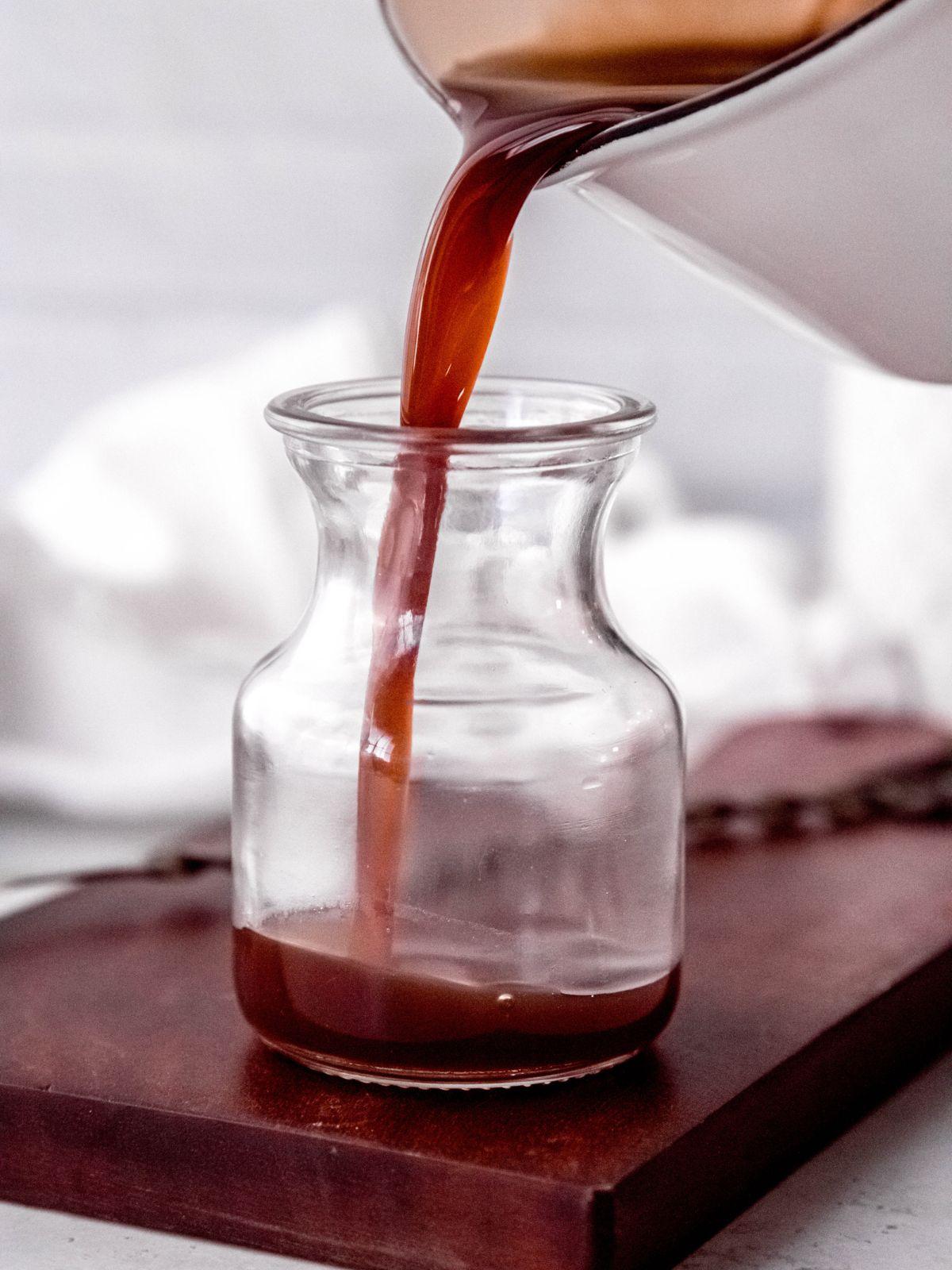 action shot of the homemade Irish cream syrup being decanted into a small glass jar.