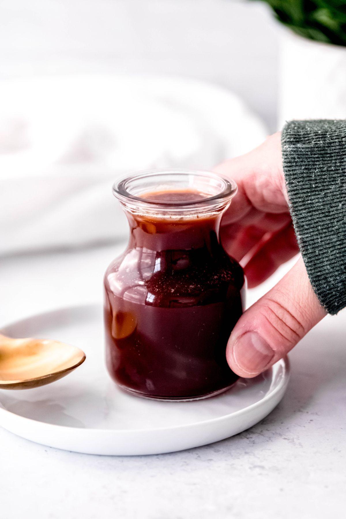 hand grabbing a small jar of Irish cream coffee syrup.