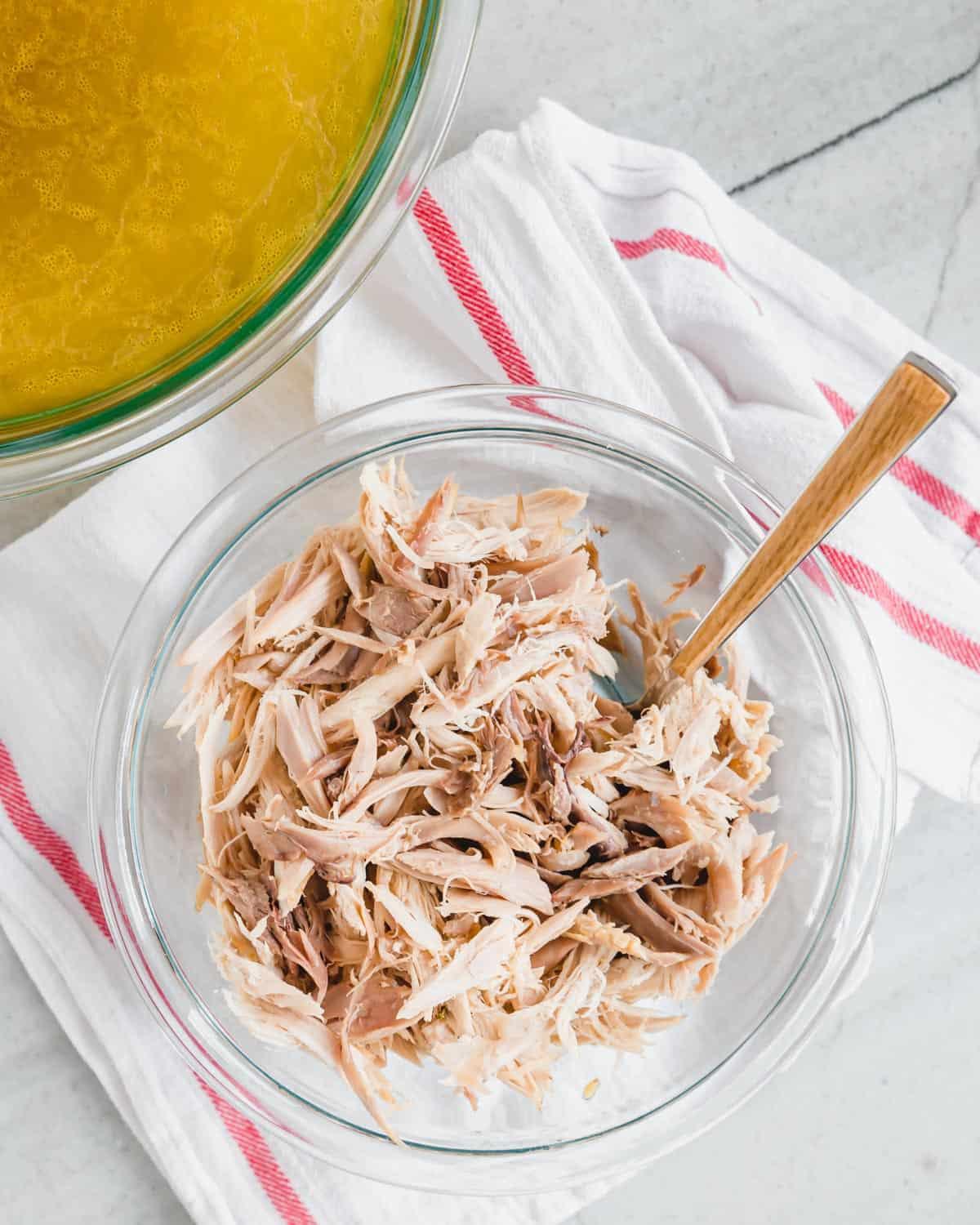 Shredded stewing hen chicken meat in a bowl with a fork.