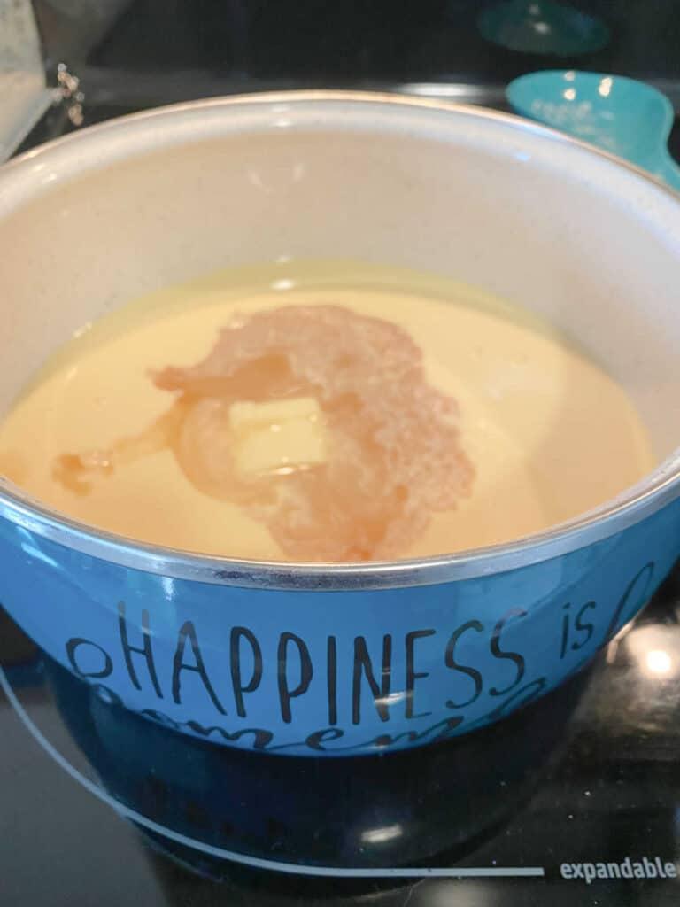 process shot - liquid ingredients are added to a medium saucepan on the stove.