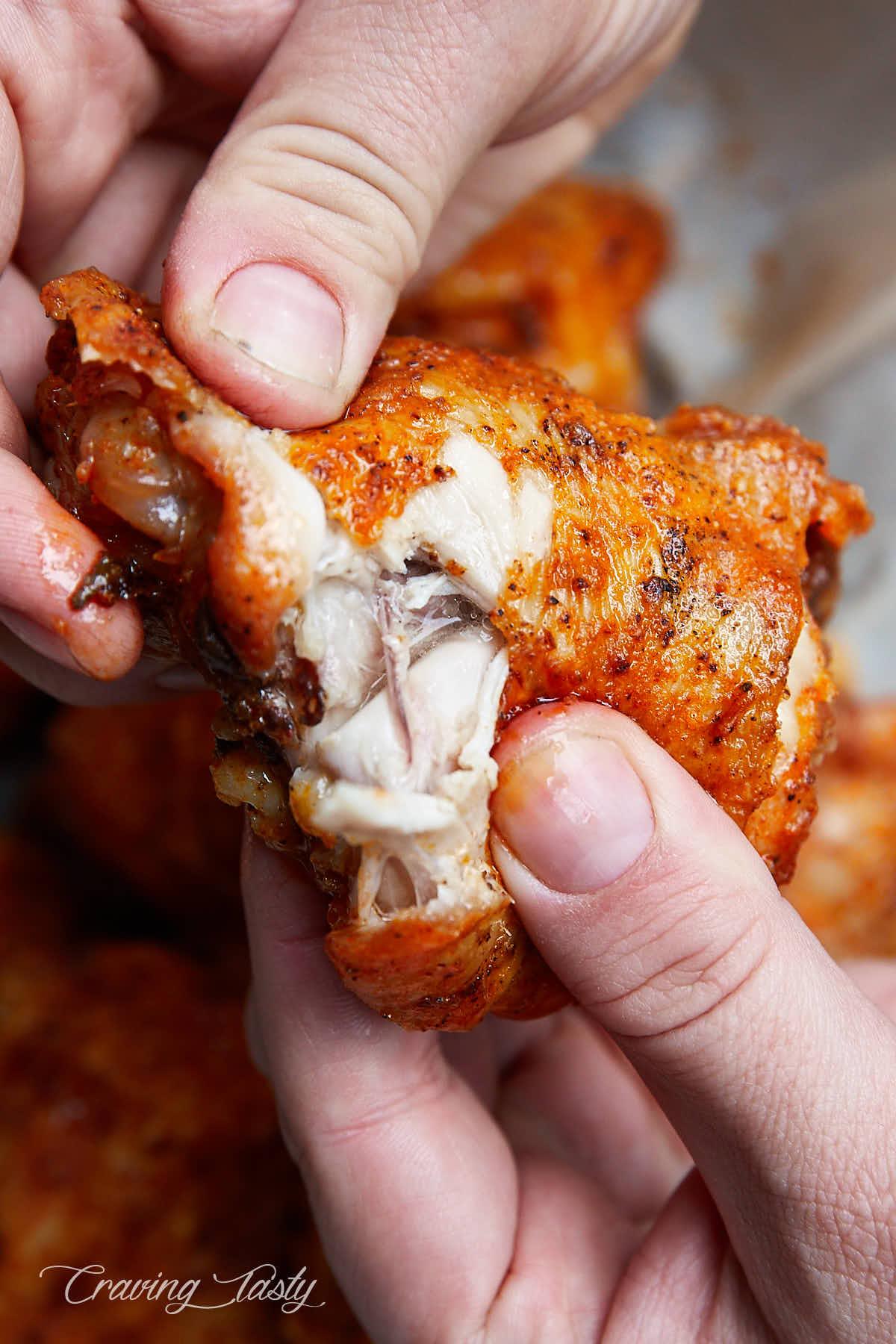 Close up of a split open crispy chicken thigh, showing juices running off.