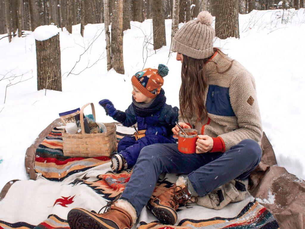 Mom and boy having picnic in winter on blanket in the snow