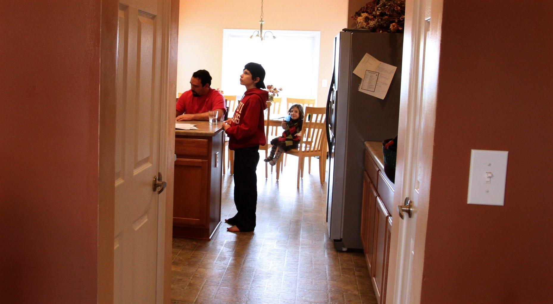 In this March 2011 file photo from the Indianapolis Star, Jake Barnett, 12, center, takes a break from studying for his college finals. In the background, Natalia Barnett sits on a kitchen chair, and Michael Barnett is seen at the kitchen island.
