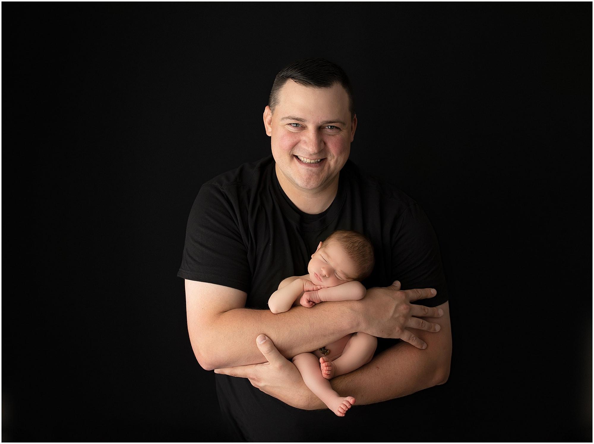 new father holds his newborn baby boy at camp hill pa newborn photography studio