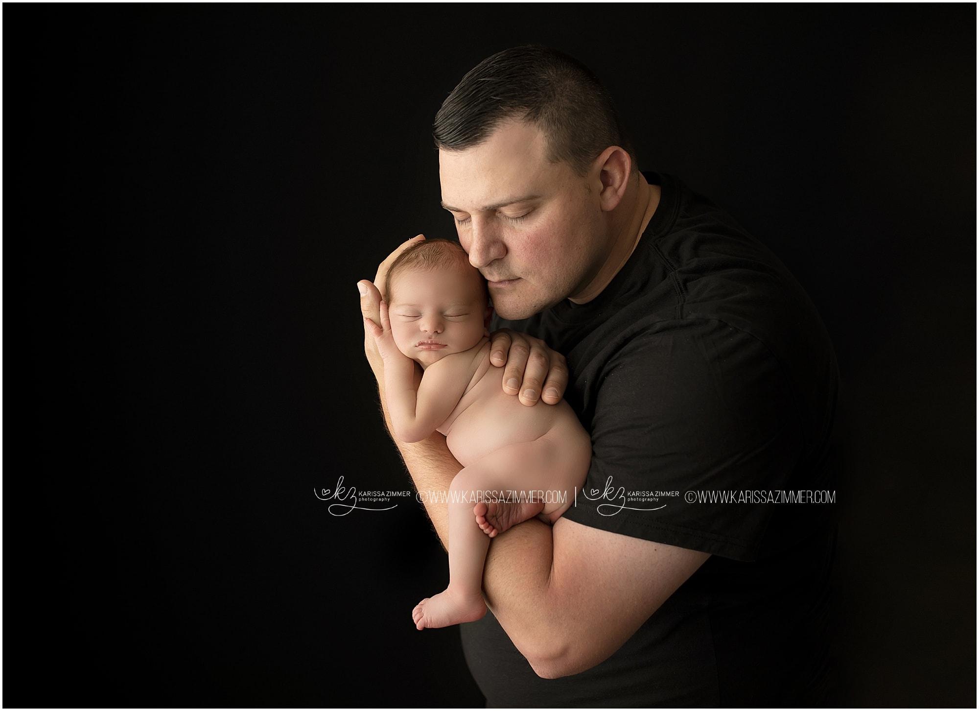 A new father cradles his newborn baby during photography session at camp hill studio